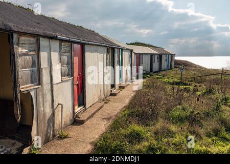 Verlassene Ferienchalets, die wegen der Abnutzung der Klippen in Brightstone Bay, Isle of Wight, aufgegeben wurden Stockfoto