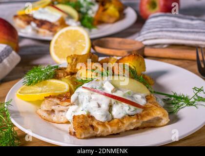 Gebratener Fisch mit Bratkartoffeln und Sauerrahm-Dressing Stockfoto