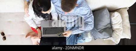 Mann und Frau sitzen in einer Umarmung auf der Couch neben mehrfarbigen Paketen stehen. Stockfoto