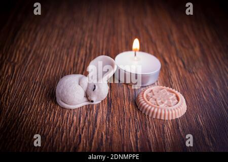 Foto dekorative schlafende Maus Figur mit brennender Kerze auf Holz Hintergrund Stockfoto