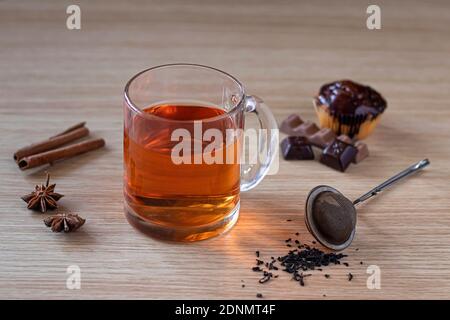 Tasse Tee mit Standard Tee Infuser Mesh Löffel. cupcake, Zimt und Sternanis. Tasse Tee und Schokolade oder Süßigkeiten Stockfoto