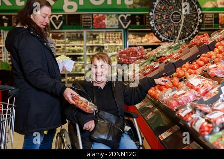 Female carer helping woman with shopping Stockfoto