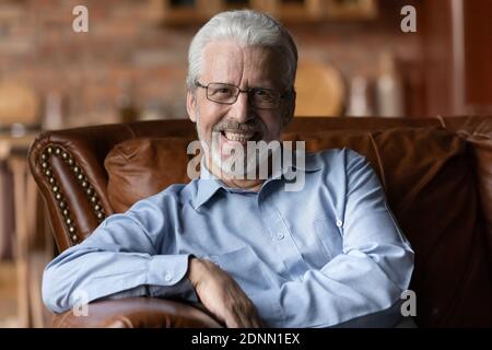 Porträt eines glücklichen Mannes mittleren Alters, der sich auf einem bequemen Sofa entspannt. Stockfoto