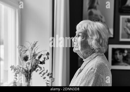 Ältere Frau, die durch Fenster Stockfoto