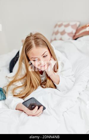 Frau im Bett mit Handy Stockfoto