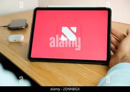 Apple News plus Logo auf dem Bildschirm des iPad Tablet Mit Smartphone iPhone Aufladen auf dem kabellosen Ladegerät und airpods im Gehäuse auf dem Hintergrund Stockfoto