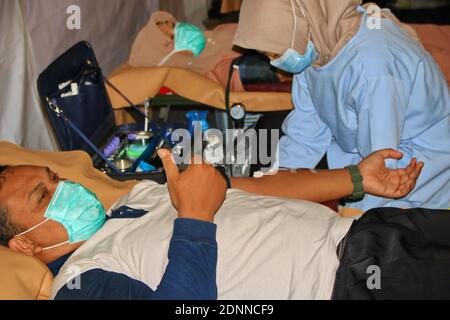 Menschen, deren Gesundheit von einem medizinischen Offizier, Batang, Indonesien, überprüft wird, 7. Dezember 2020 Stockfoto