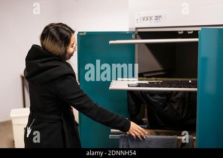 Frau, die Kleidung in den Trockner legt Stockfoto