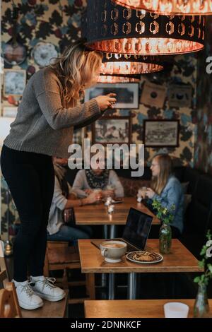 Woman taking photo in cafe Stock Photo