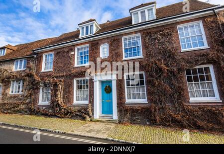 Reihenhaus im georgianischen Stil (Church Hill House) in Church Hill, Midhurst, West Sussex, im Winter mit einem Weihnachtskranz an der blauen Haustür Stockfoto