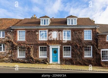 Reihenhaus im georgianischen Stil (Church Hill House) in Church Hill, Midhurst, West Sussex, im Winter mit einem Weihnachtskranz an der blauen Haustür Stockfoto