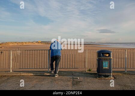 GROSSBRITANNIEN / Wales /Porthcawl/ Rückansicht eines männlichen Mannes mit Blick auf Coney Beach. Porthcawls wirtschaftliche Veränderungen, insbesondere der postindustrielle Rückgang . Stockfoto