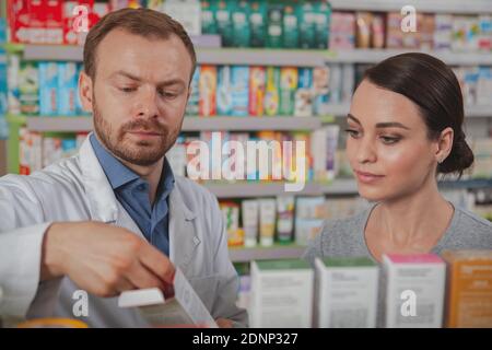 Beautiful young woman talking to the chemist, shopping at the drugstore. Attractive female customer buying medicament or cosmetics at pharmacy Stockfoto