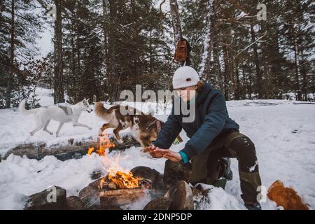 Mann, der im Winter in der Nähe des Holzfeuers sitzt Stockfoto