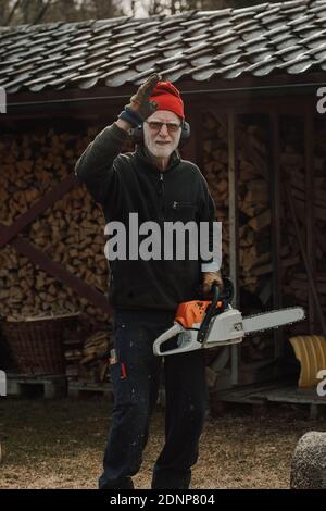 Senior man holding chainsaw Stockfoto