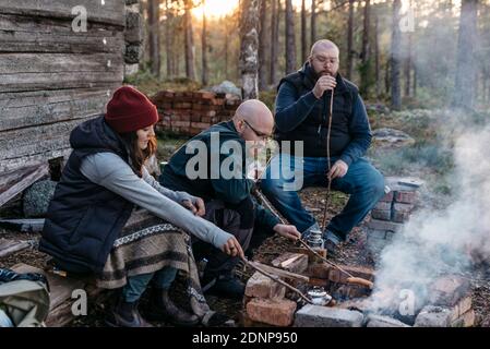 Leute, die Würstchen über dem Holzfeuer zubereiten Stockfoto