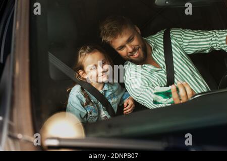 Vater mit Tochter im Auto nimmt Selfie Stockfoto