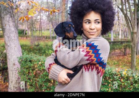 Afroamerikanische Mädchen sitzen und umarmt ihren Hund in der park im Herbst Stockfoto