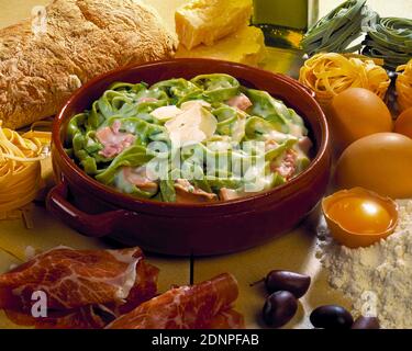 Grüne Pasta Carbonara in Terrakotta-Schüssel mit Zutaten Stockfoto