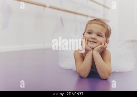 Nettes glückliches kleines Mädchen lächelnd wegschauen, schröpfen ihr Gesicht, kopieren Raum. Liebenswert kleine Ballerina Ruhe nach Ballett-Tanzkurs im Studio. C Stockfoto