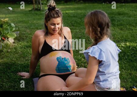 Mutter mit Tochter sitzt auf dem Rasen Stockfoto
