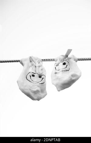 Zwei Socken mit einem Smiley Emoticon hängen an einem Seil mit Wäscheklammern, bw Foto Stockfoto