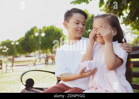 Nettes kleines Mädchen erhalten Überraschung Geschenk von ihrem Bruder. Glücklich junge asiatische junge gratulierende seine kleine Schwester, die ihr ein Geschenk, Kopie Raum Stockfoto