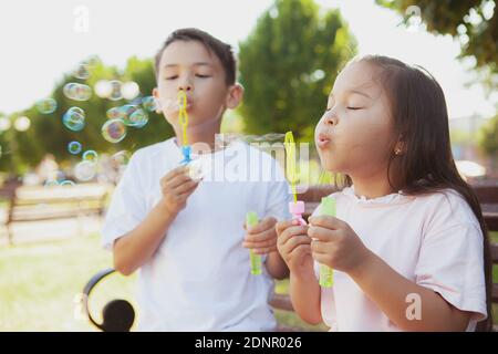 Glücklich niedlichen kleinen Kindern Blasen im Freien im Park. Schöne asiatische Kinder mit Spaß, Blasen Blasen. Livestyle, unbeschwertes Kindheitskonzept Stockfoto