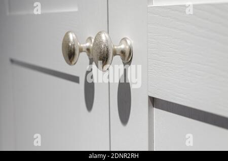 Möbelbeschläge. Türgriffe aus Metallic-Silber mit scharfen Schatten an der weißen Fassade Stockfoto