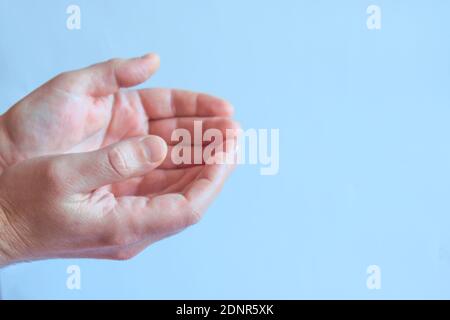 Schöne leere Männerhände halten die Handflächen auf einem blauen Hintergrund hoch. Seitenansicht Stockfoto