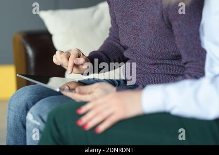 Mann und Frau sitzen auf der Couch und schauen hinein Digitales Tablet Stockfoto