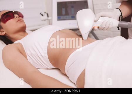 Frau, die unerwünschte Haare auf ihrem Bauch beim Laser entfernt Enthaarungsbehandlung Stockfoto