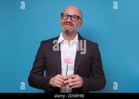 Reifer Mann im Anzug mit einer Blume. Studio auf blauer Wand. Stockfoto