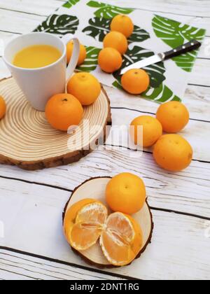Orangen, Mandarinen und Orangensaft auf einem Holztisch Stockfoto