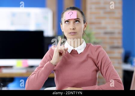 Pinker Aufkleber mit Fragezeichen, das an der Stirn der Frau klebt Stockfoto