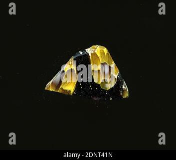 Fragment eines Gefäßes, Glas, millefiori-Technik, Gesamt: Höhe: 0.80 cm; Breite: 1.30 cm, Behälter, Lagerung, Küchenarbeit, Trinken und Barware, florale Ornamente, frühe Kaiserzeit, EINE leichte Krümmung des Glasfragments ermöglicht die Zuordnung zu einem Gefäß. Das violette Glas ist mit Blumen in millefiori-Technik verziert. Die Blüten bestehen aus einem weißen Kern mit transparentem Rand, um den runde transparente Blütenblätter mit gelben Konturen angeordnet sind. Für die Herstellung wurden verschiedenfarbige Gläser zu Rohren und Stäben geformt. Stockfoto