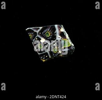 Fragment eines Gefäßes, Glas, millefiori-Technik, Gesamt: Höhe: 1.70 cm; Breite: 2.10 cm, Behälter, Lagerung, Küchenarbeit, florale Ornamente, frühkaiserliche Zeit, EINE leichte Krümmung des Glassfragmentes ermöglicht die Zuordnung zu einem Gefäß, möglicherweise einer Schüssel. Der violette Scherbe ist durchsetzt mit einem Gitter aus weißen Linien, die an Waben erinnern. In der Mitte befindet sich ein blauer Punkt mit einer gelben Umrandung, um den runde weiße Punkte als Blütenblätter gruppiert sind. Für die Herstellung wurden verschiedenfarbige Gläser zu Rohren und Stäben geformt. Stockfoto