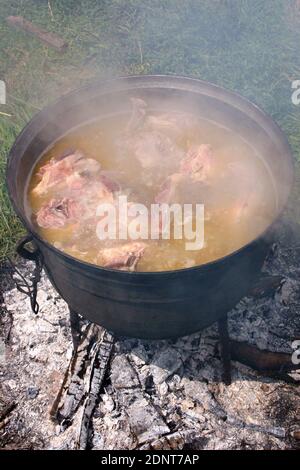 Shurpa bereitet sich in einem Kessel auf dem Scheiterhaufen vor. Eine große Kessel mit Zutaten für Shurpa, kochen über einem Lagerfeuer Stockfoto