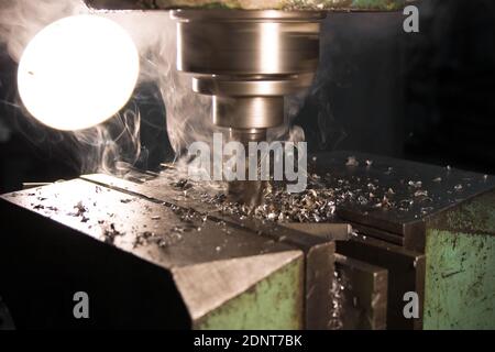 Fräsen eines Metallteils. Auf einer alten vertikalen Fräsmaschine wird ein Metallteil bearbeitet Stockfoto