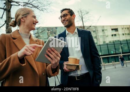 Gemischte Rennen Geschäftspartner lächeln, während Business-Pläne zu diskutieren Recherche Auf dem digitalen Tablet zu Fuß zur Arbeit Stockfoto