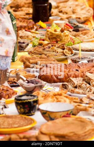 Slawischer Urlaub Maslenitsa (auch bekannt als Butter Lady, Butter Week, Crepe Week oder Cheesefare Woche) - ein festlicher Tisch mit Pfannkuchen und Kuchen Stockfoto