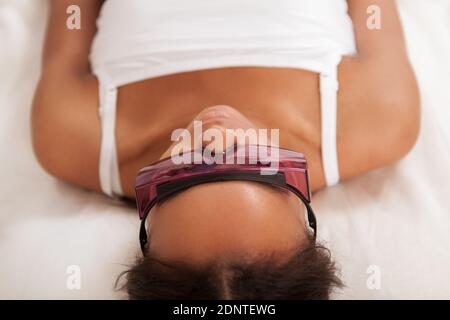 Nahaufnahme einer jungen afrikanischen Frau mit Schutzbrille Im Laser-Friseursalon Stockfoto