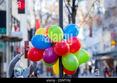 Cologne, Germany. 18th Dec, 2020. A woman takes pictures of balloons on the Schildergasse, which are supposed to indicate the open food department of a large department store. Credit: Rolf Vennenbernd/dpa/Alamy Live News Stock Photo