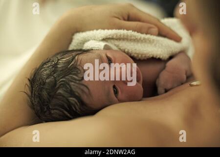 Ein neugeborenes Baby im Besitz seiner Mutter Momente nach der Geburt UK Stockfoto