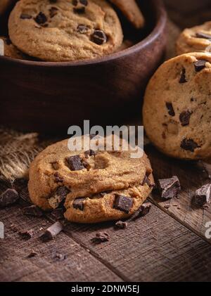 Chocolate Chip Cookies und Schokoladenstücke auf einem rustikalen Holz Tisch mit Schale Kekse im Hintergrund Stockfoto
