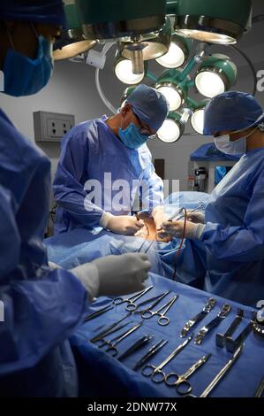 Chirurgische Team tun ästhetische Chirurgie im Operationssaal. Ärzte tun kosmetische Chirurgie, während Assistent neben OP-Tisch mit medizinischen Instrumenten stehen. Konzept der Medizin und plastische Chirurgie. Stockfoto