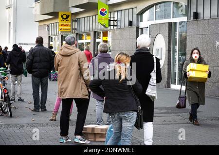 Dortmund, 18. Dezember 2020: Kunden warten auf dem Bürgersteig vor einer Filiale der Deutschen Post / DHL in Dortmund. Aufgrund der Einschränkungen der zweiten Sperrung der Corona-Pandemie dürfen nur 3 Kunden gleichzeitig in dieser Filiale bleiben. Stockfoto