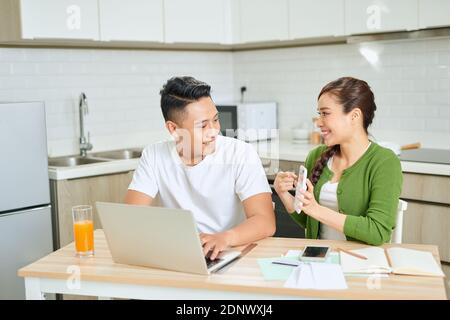 Junges Paar verwaltet Finanzen, Überprüfung ihrer Bankkonten mit Laptop-Computer und Rechner in der modernen Küche. Stockfoto