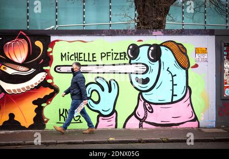 Ein Mann mit einer schützenden Gesichtsmask geht an Graffiti vorbei, das 'Michelle Pfizer' im Stadtzentrum von Edinburgh liest. Stockfoto