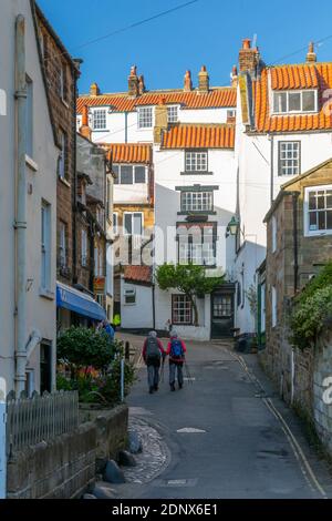 Blick auf Wanderer und weiß getünchte Häuser an der New Road in Robin Hood's Bay, North Yorkshire, England, Großbritannien, Europa Stockfoto